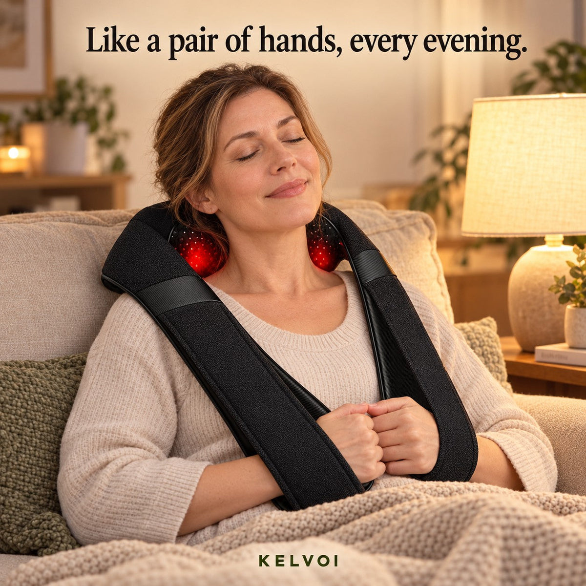 Woman relaxing on a couch in the evening wearing the KneadWrap massager